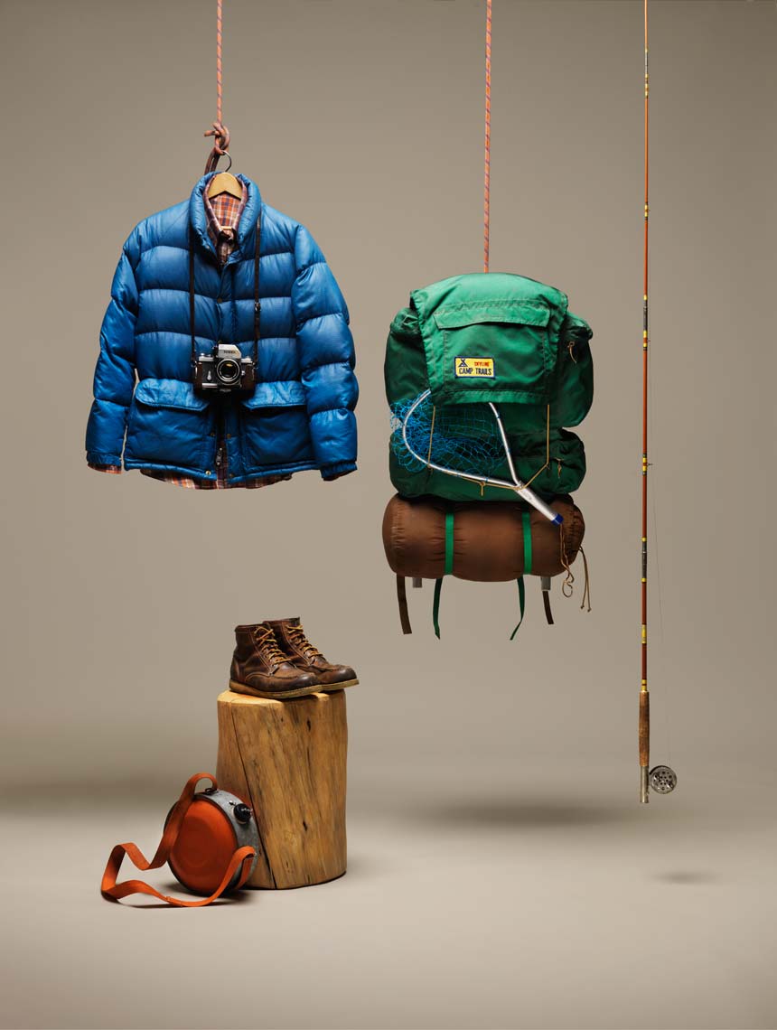 backpacking gear fishing pole and puffy coat on a tan background