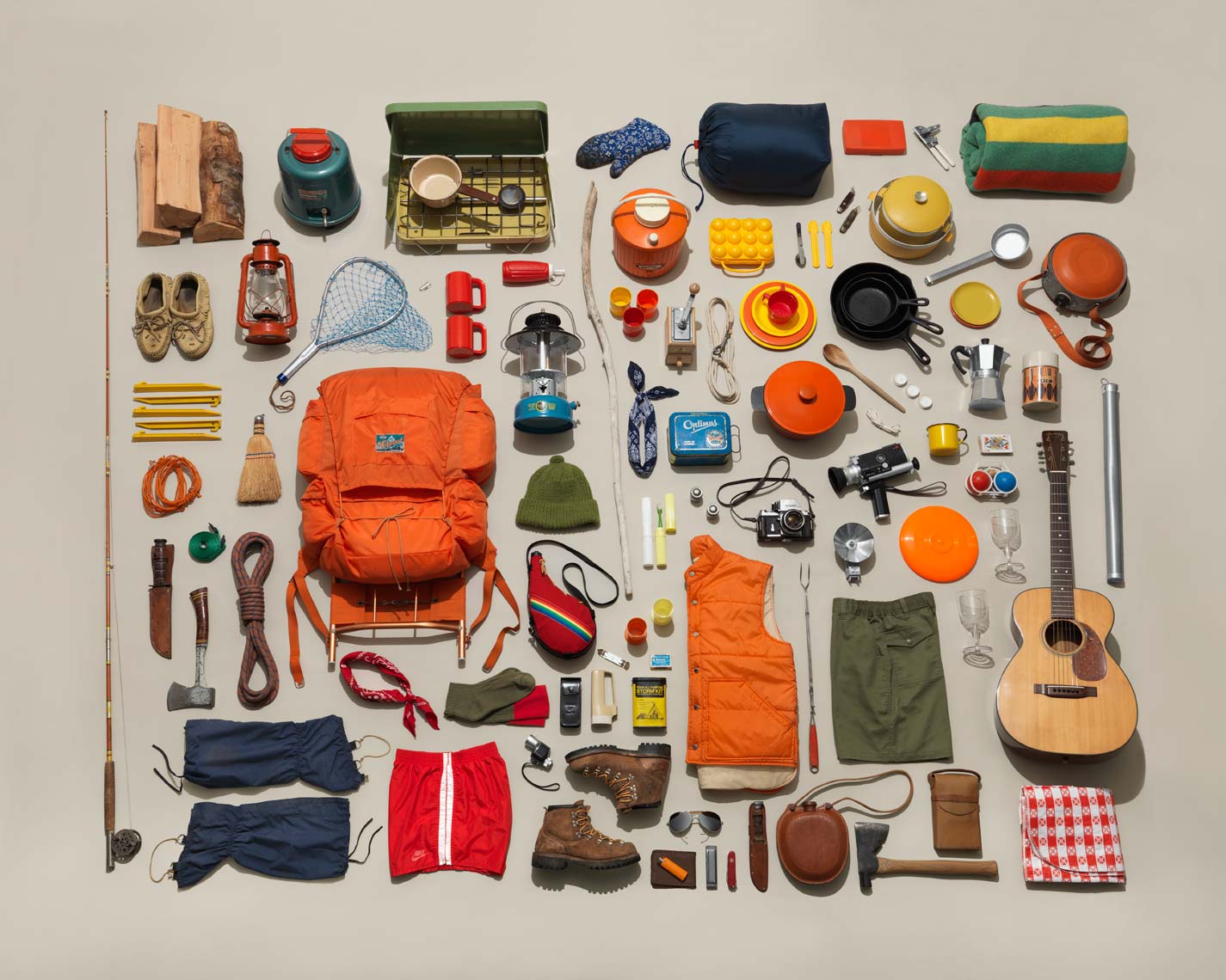 classic camping gear organized neatly on tan background 