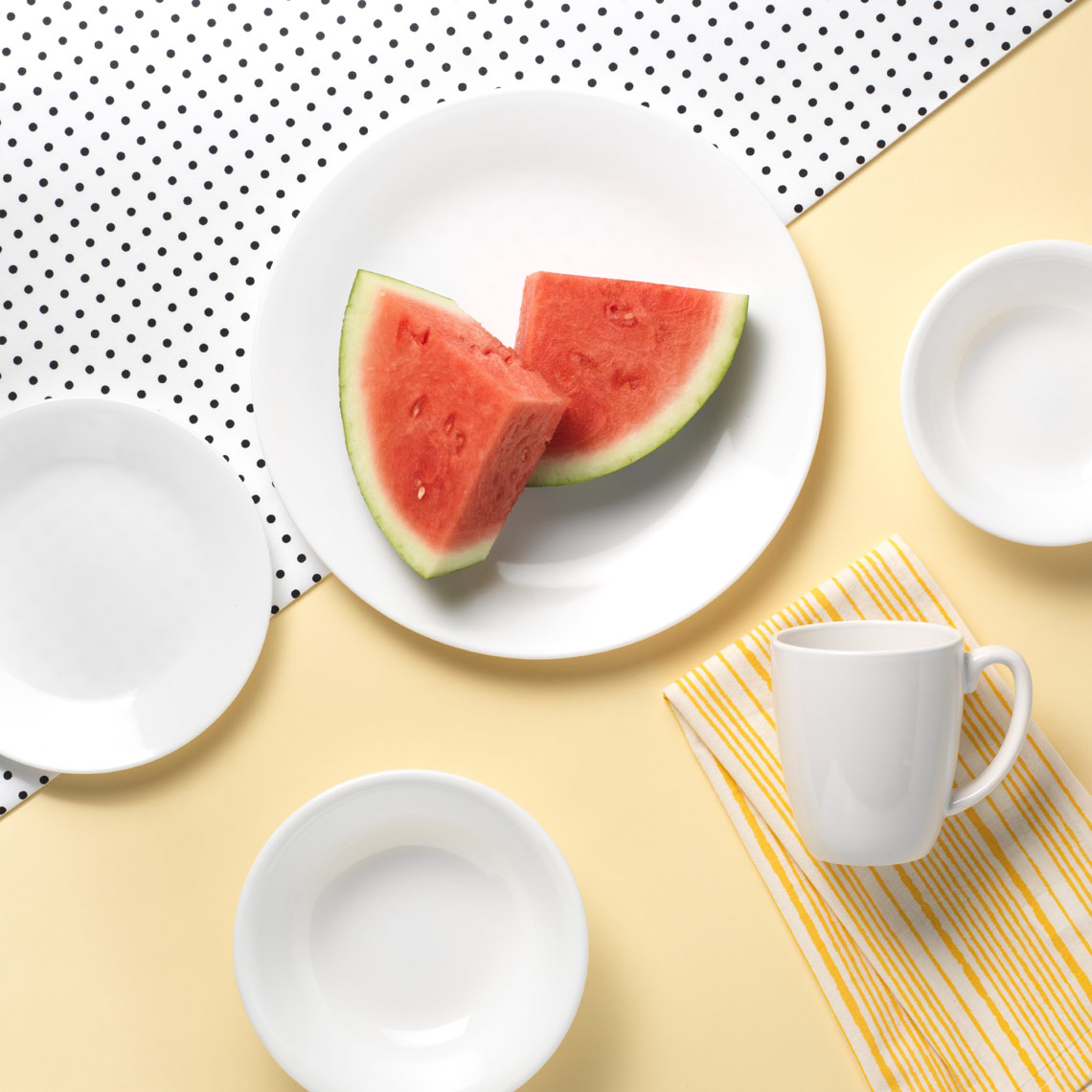 plates on a yellow black and white polka dot table with watermelon 