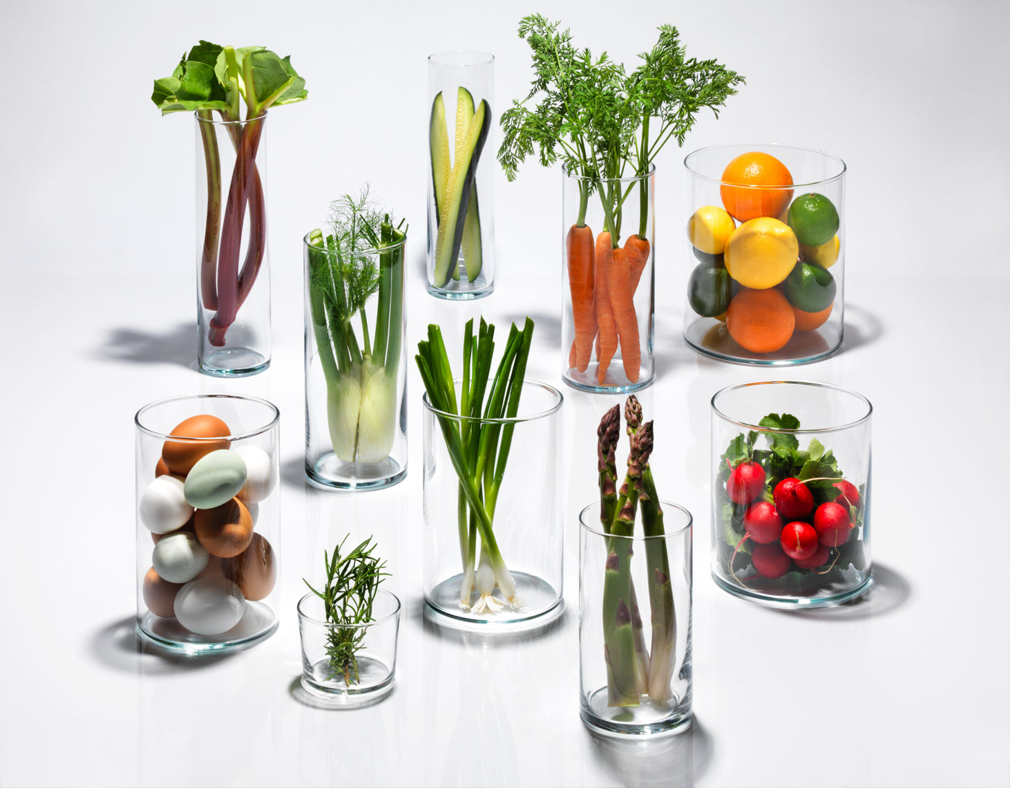 vegetables in clear glass cylinders on white